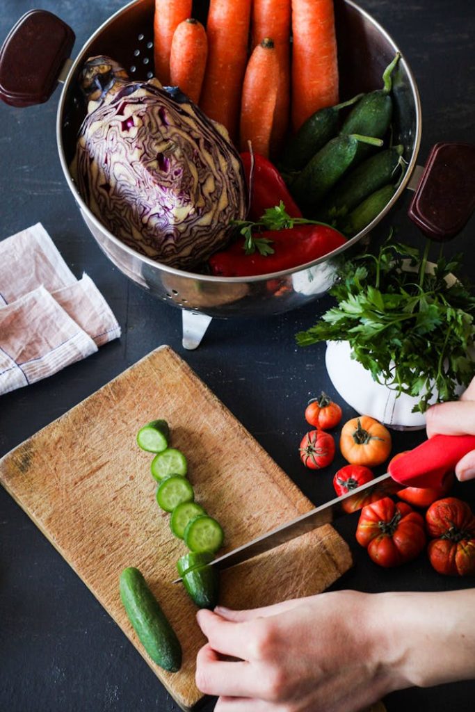 Des concombres coupés en rondelles et des légumes frais sur une planche à découper pour préparer des repas sains.